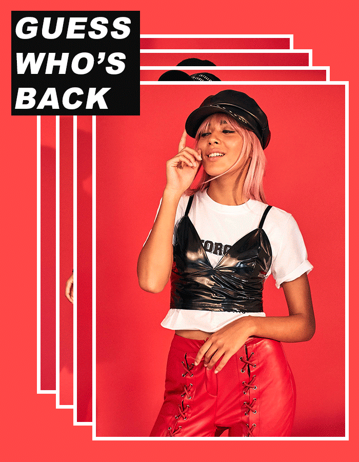 Woman with pink hair, wearing black top, red pants. Text: "Guess Who's Back".